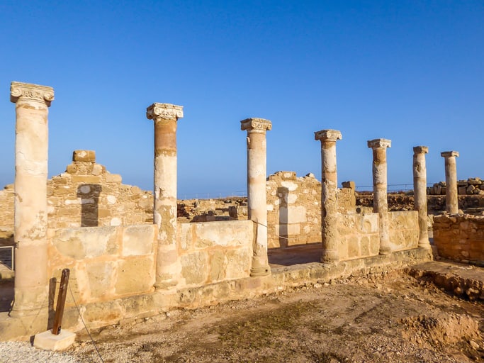 Ancient stone ruins with six standing columns and partial walls under a clear blue sky—one of the fascinating things to do in Paphos.