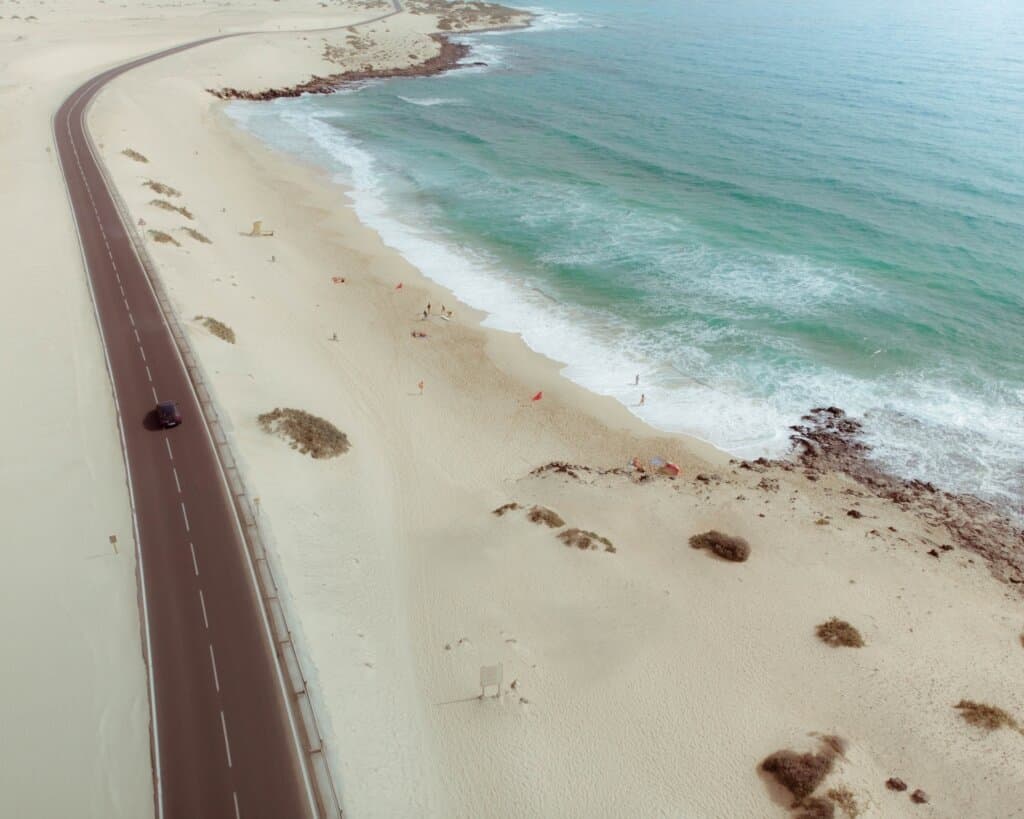 Aerial view of a single road snaking through a white sand landscape in Corralejo natural park