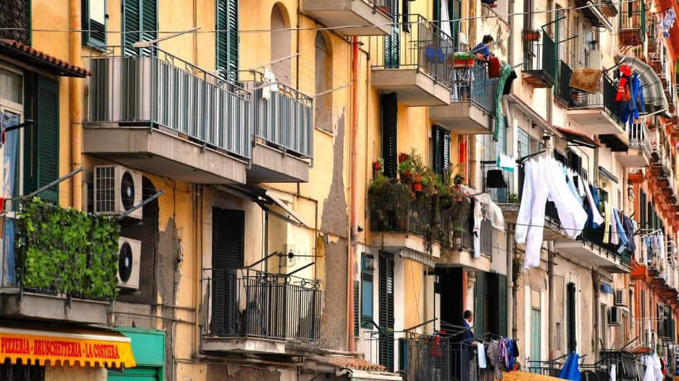 a row of buildings with balconies and balconies with laundry hanging in Italy