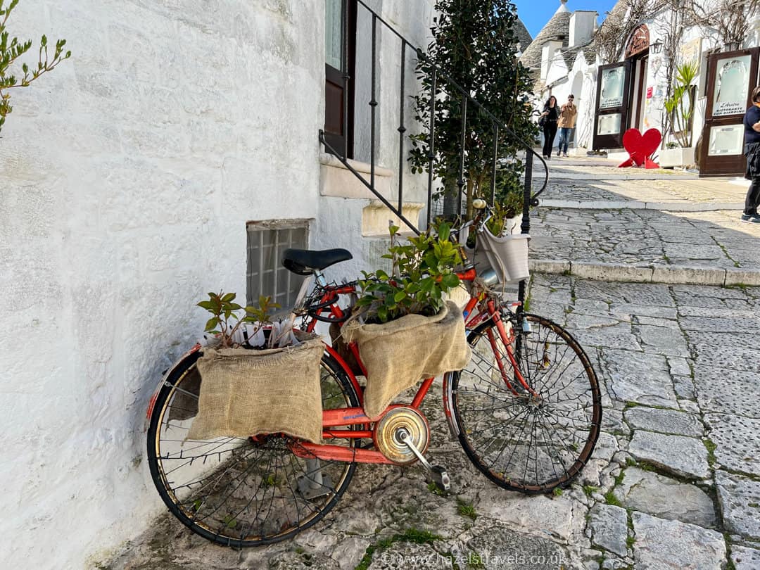 a red bike parked next to a white building.