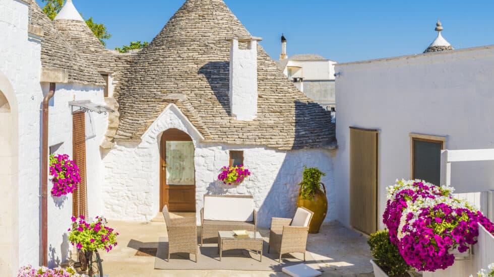 a trulli house in Puglia Italy with pink flowers.