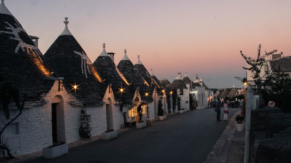 Road in Alberobello with white houses with conical rooftops