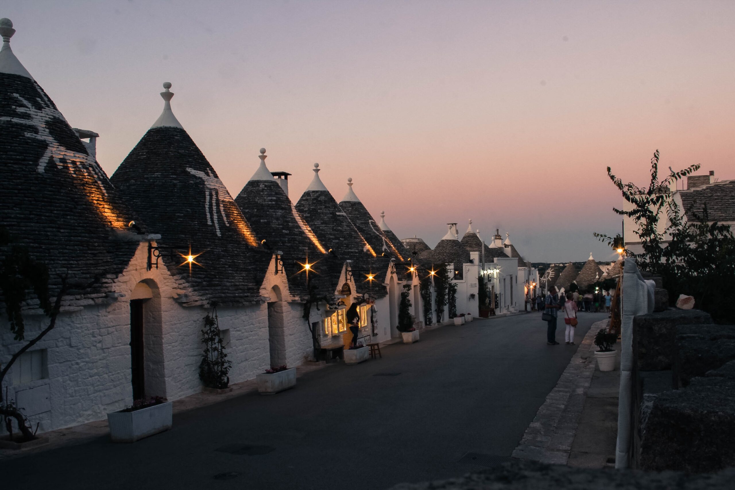 Road in Alberobello with white houses with conical rooftops