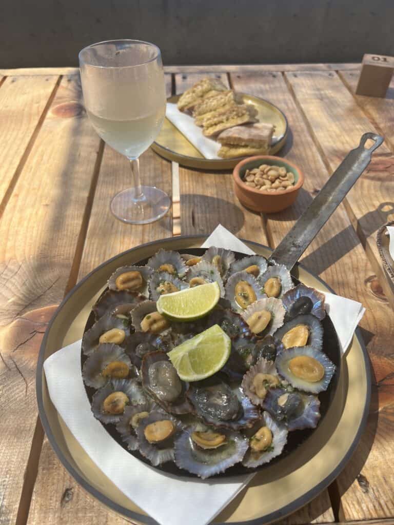 A plate of limpets on a wooden table.