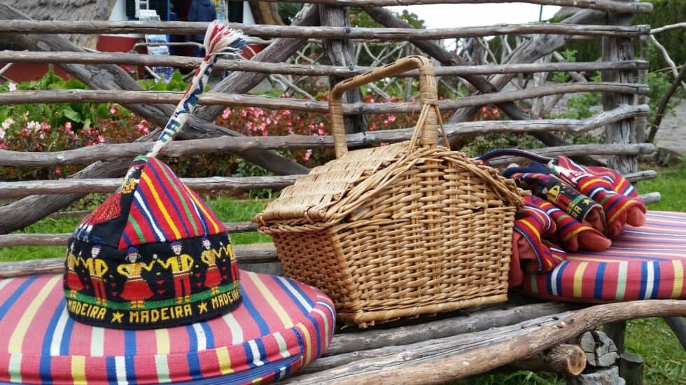 A Madeira souvenir bench with baskets and hats on it.