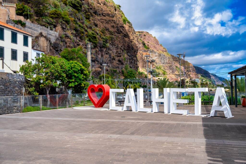 A sign with the word Calheta in front of a mountain, showcasing one of the exciting things to do in Calheta.
