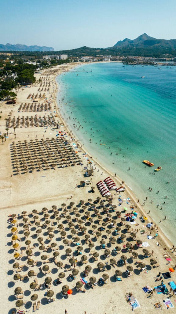 Beach in Mallorca with parasols and turquoise waters.