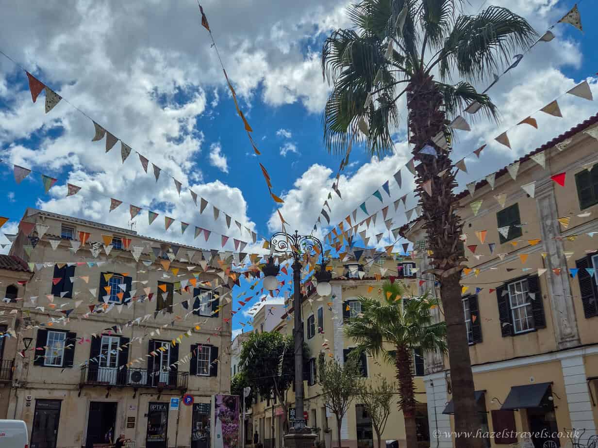 Menorca town of Mahon decorated with-bunting and palm trees in street.